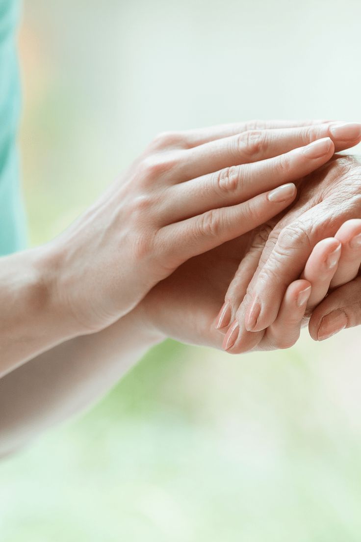 Friendly aged care support staff holding a patient's hand